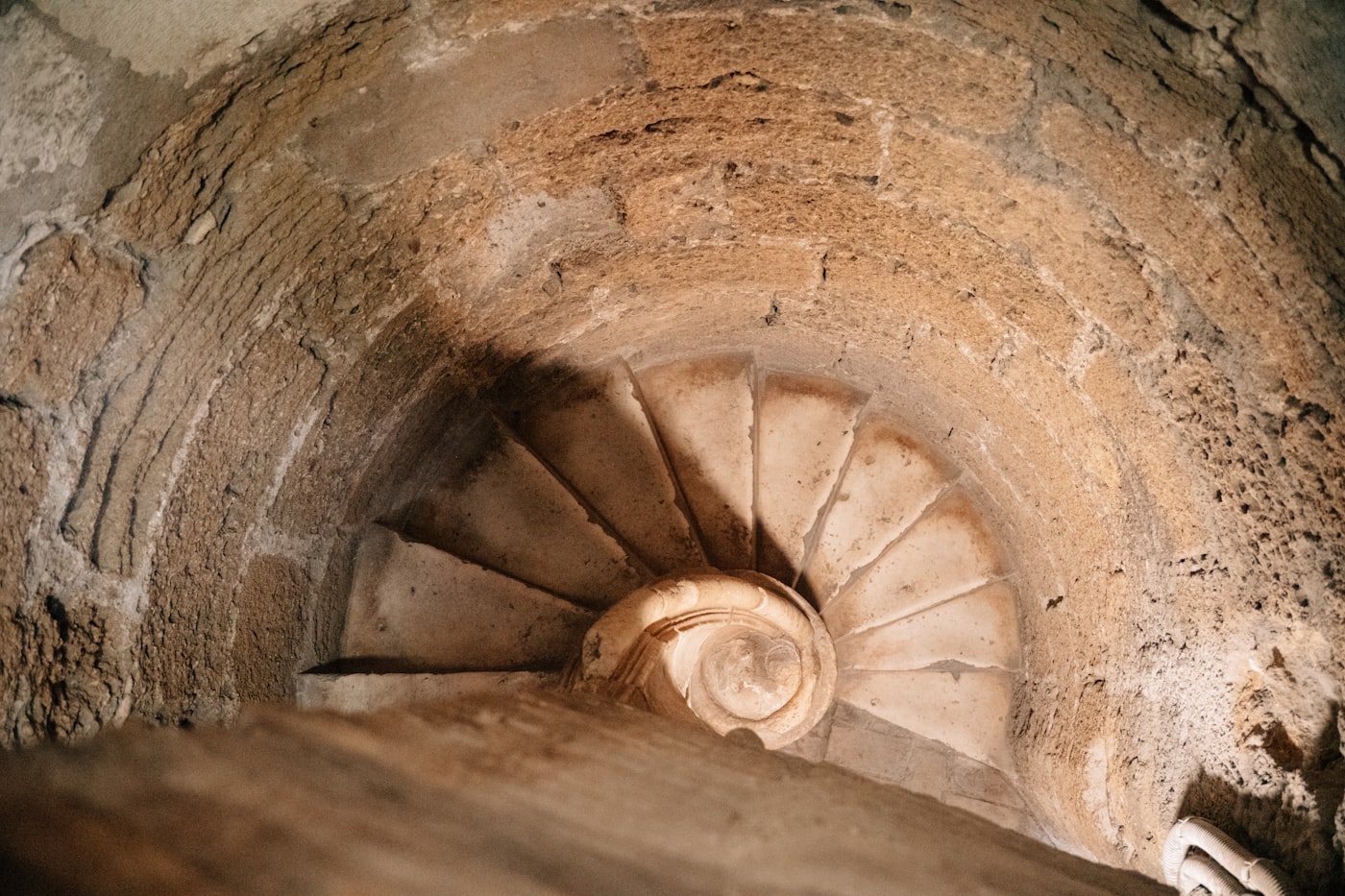 Escalera de caracol de piedra vista desde arriba, con los peldaños desgastados hacia el centro.